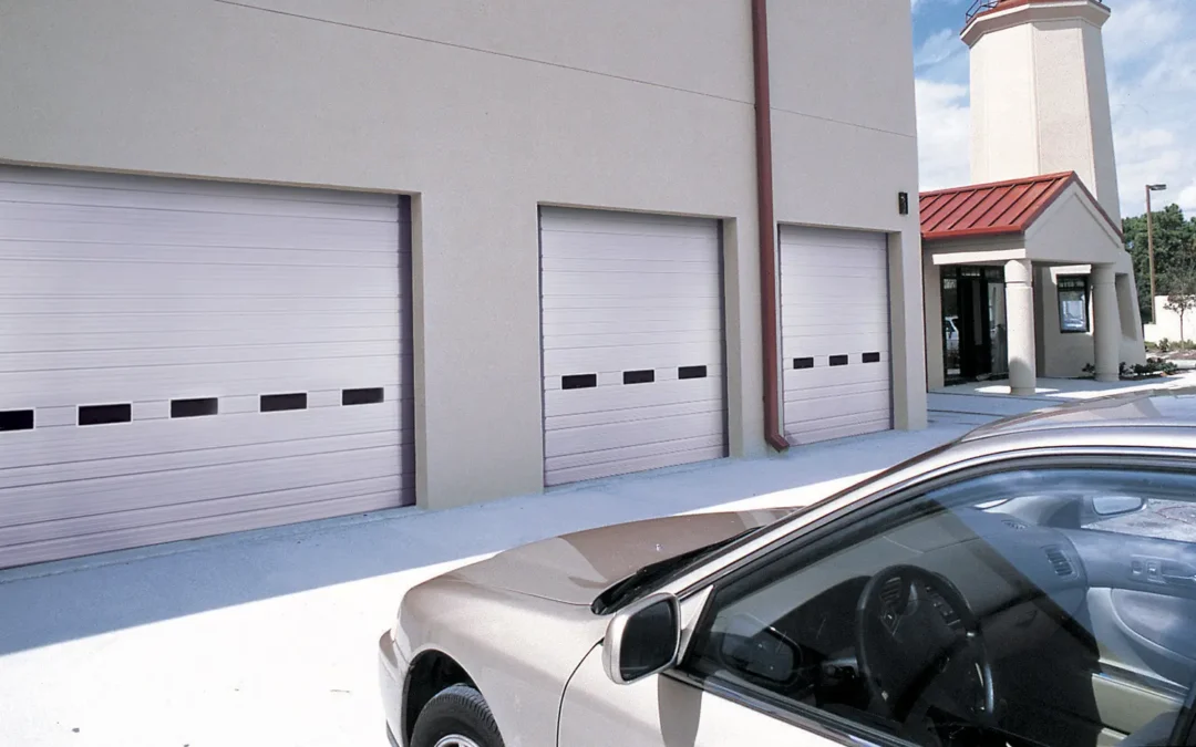 Three closed garage doors at a commercial building with a car parked in the foreground.