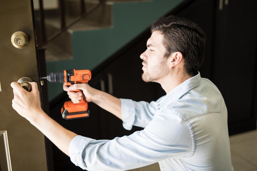 profile-view-attractive-handyman-using-power-drill-fix-door-knob-house_662251-2747
