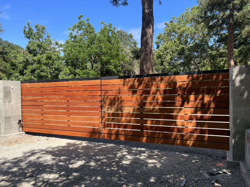 A modern wooden fence casting shadows on a sunny day.